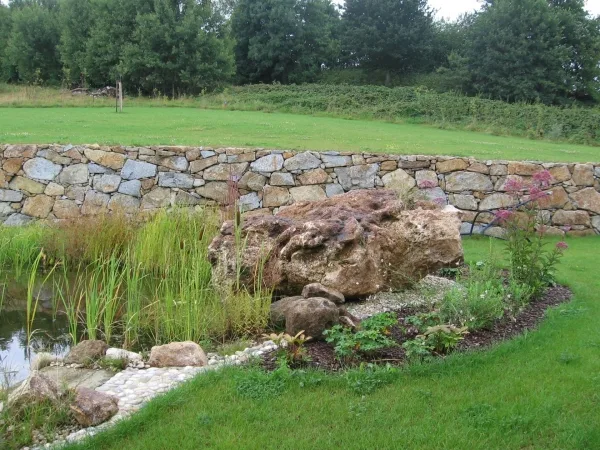 Natursteinmauer mit bepflanztem Teich