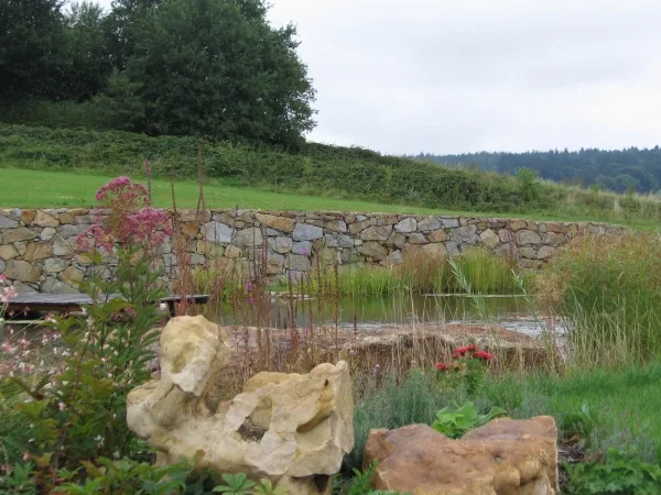 Teichanlage vor einer langen Natursteinmauer