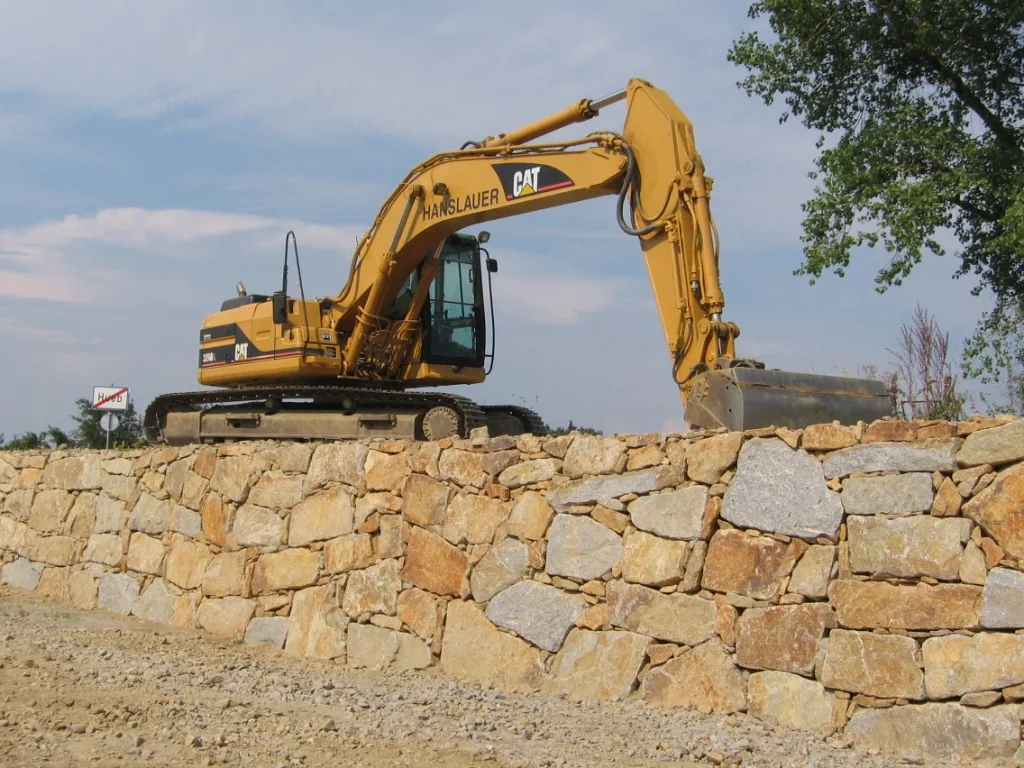 CAT-Kettenbagger von Hanslauer auf einer fertigen Natursteinmauer